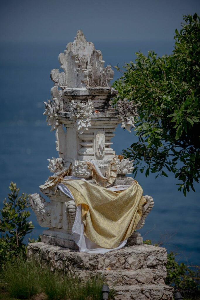 Traditional stone shrine on a cliffside overlooking the ocean in Bali.