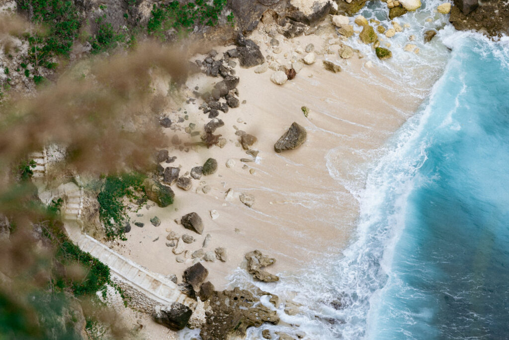 Aerial view of a sandy beach bay with breaking waves in Bali.