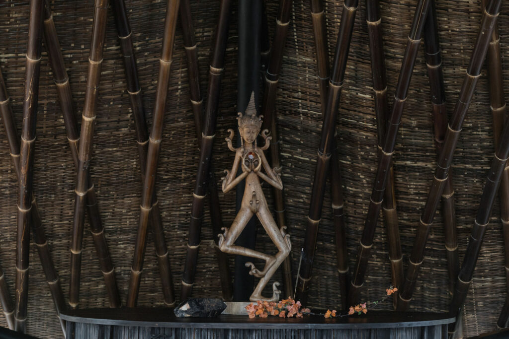 Silhouette of a traditional statue against dark textured surroundings in Bali.