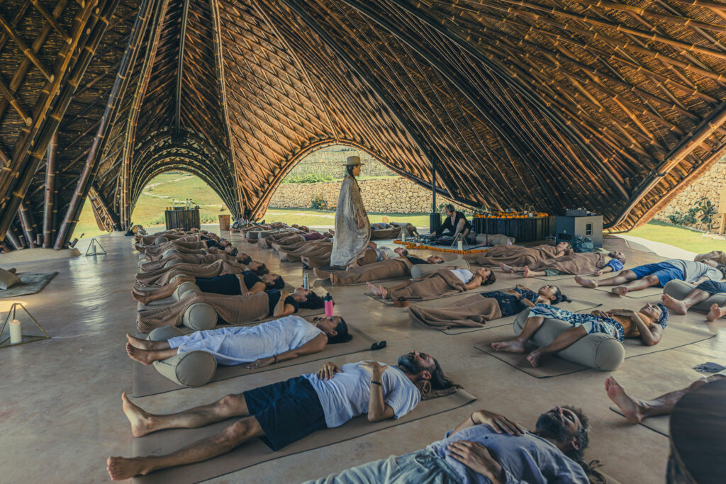Guests relaxing during a breath work session in a bamboo pavilion in Bali.