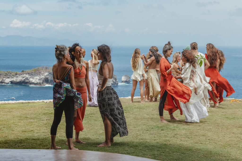 Retreat guests gathering on a lawn with ocean views in Bali.