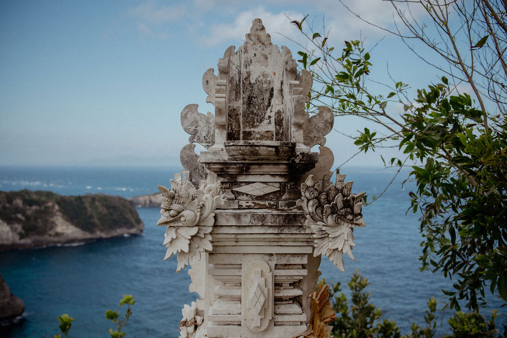 Multi-tiered traditional stone shrine overlooking the ocean in Bali.